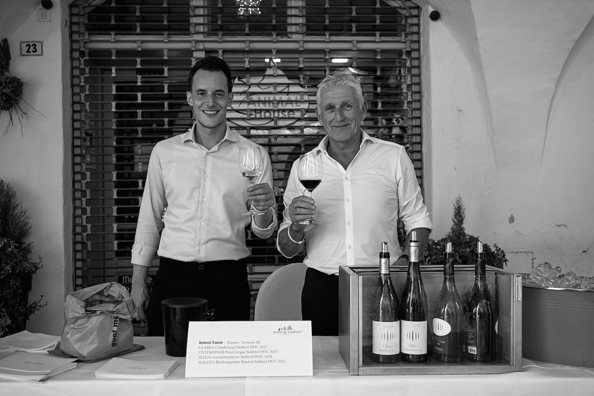 Zwei Vertreter von Kellerei Tramin stehen hinter einem Tisch und präsentieren ihre Weine.