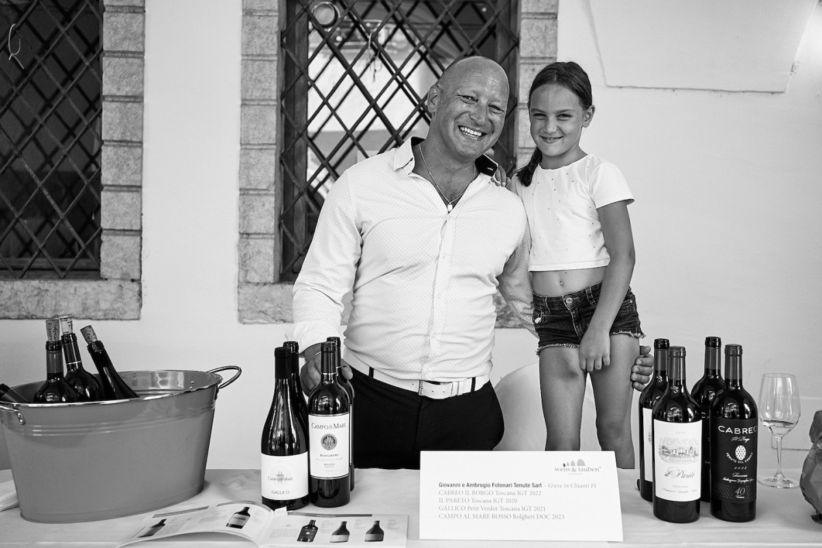 Ein Vertreter von Giovanni e Ambrogio Folonari Ternute Sart posiert gemeinsam mit einer Besucherin und zeigt eine Weinflasche.