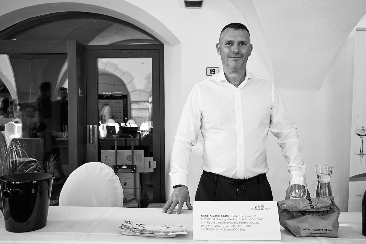 Ein Vertreter von Kellerei K. Martini und Sohn steht hinter einem Tisch und präsentiert Weine.