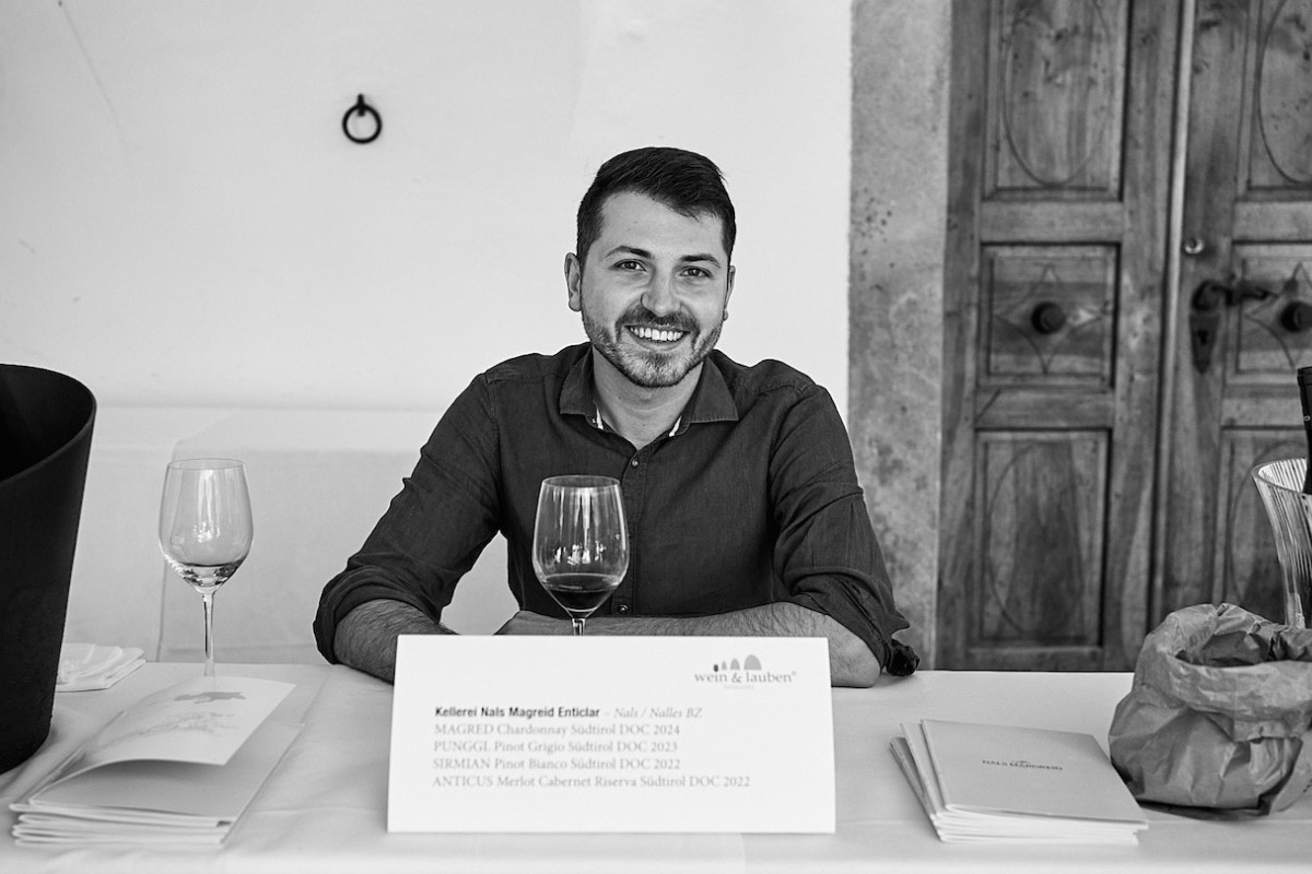 Ein Vertreter von Kellerei Nals Margreid steht hinter einem Tisch und präsentiert Weine.